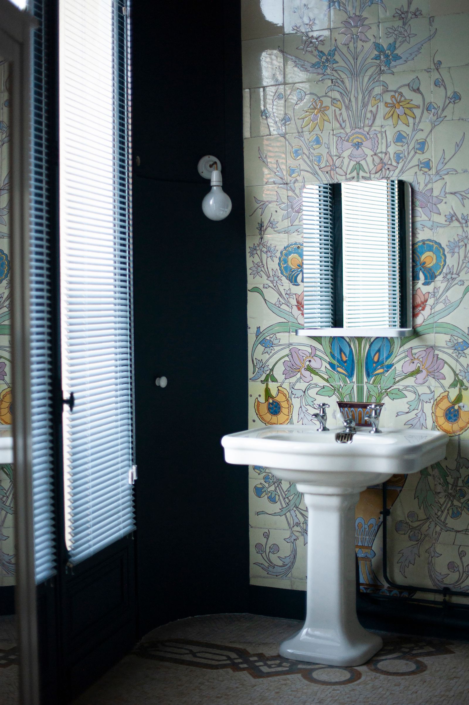 bagno con lavabo stile vintage parete piastrelle a fiori specchio applique