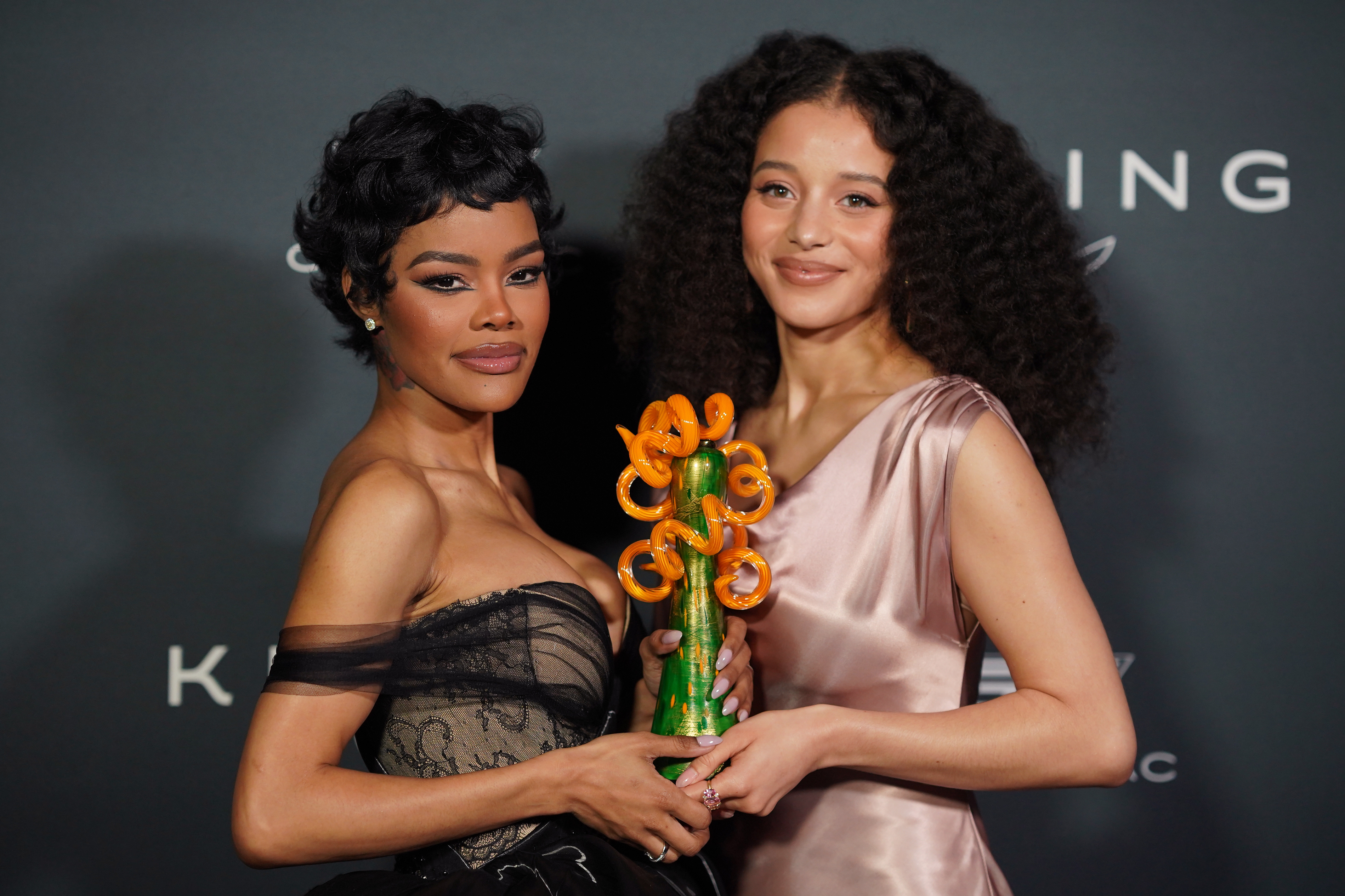 Teyana Taylor, left, and Chase Infiniti pose in the press room with Leonardo DiCaprio's desert palm achievement award for "One Battle After Another" during the 37th Palm Springs International Film Festival Film Awards on Saturday, Jan. 3, 2026 at ...