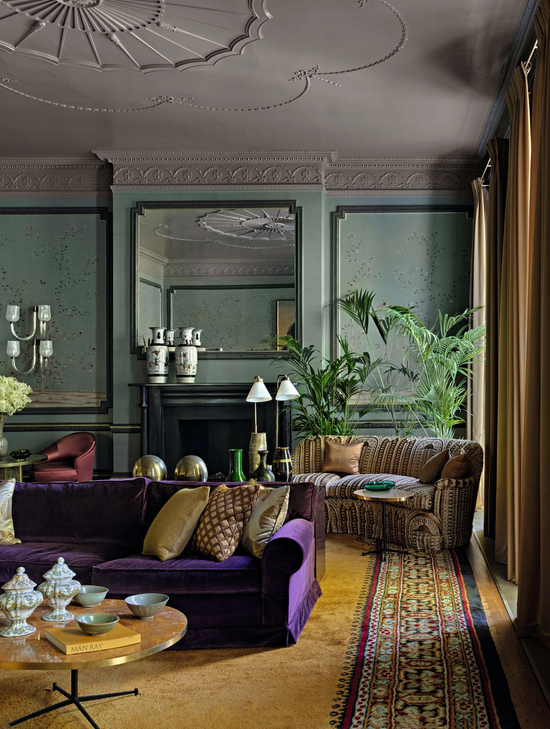 Salotto divano viola cuscini tappeto giallo con decorazioni tavolino tondo in legno vasi divano a righe camino nero...