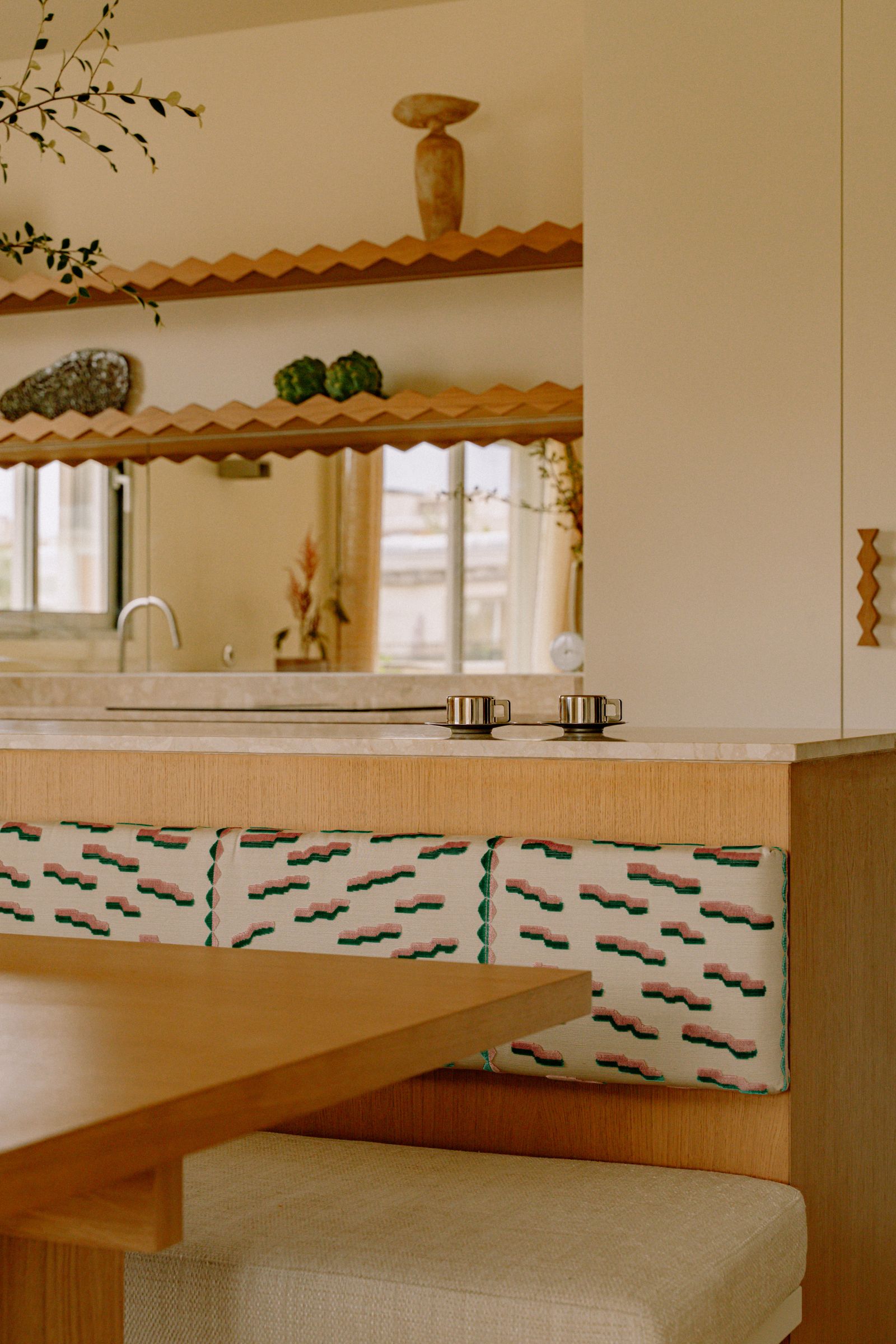 piccolo spazio cucina in legno chiaro con isola e panca mensole con motivo smerlato paraschizzi a specchio