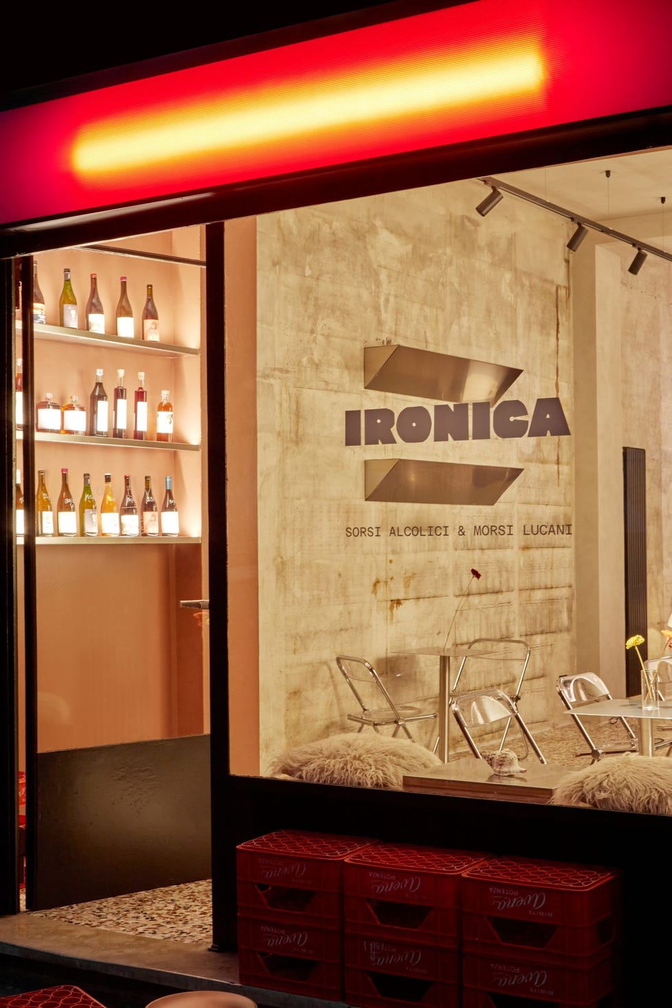 exterior view of a bar named ironica featuring bottles and seating