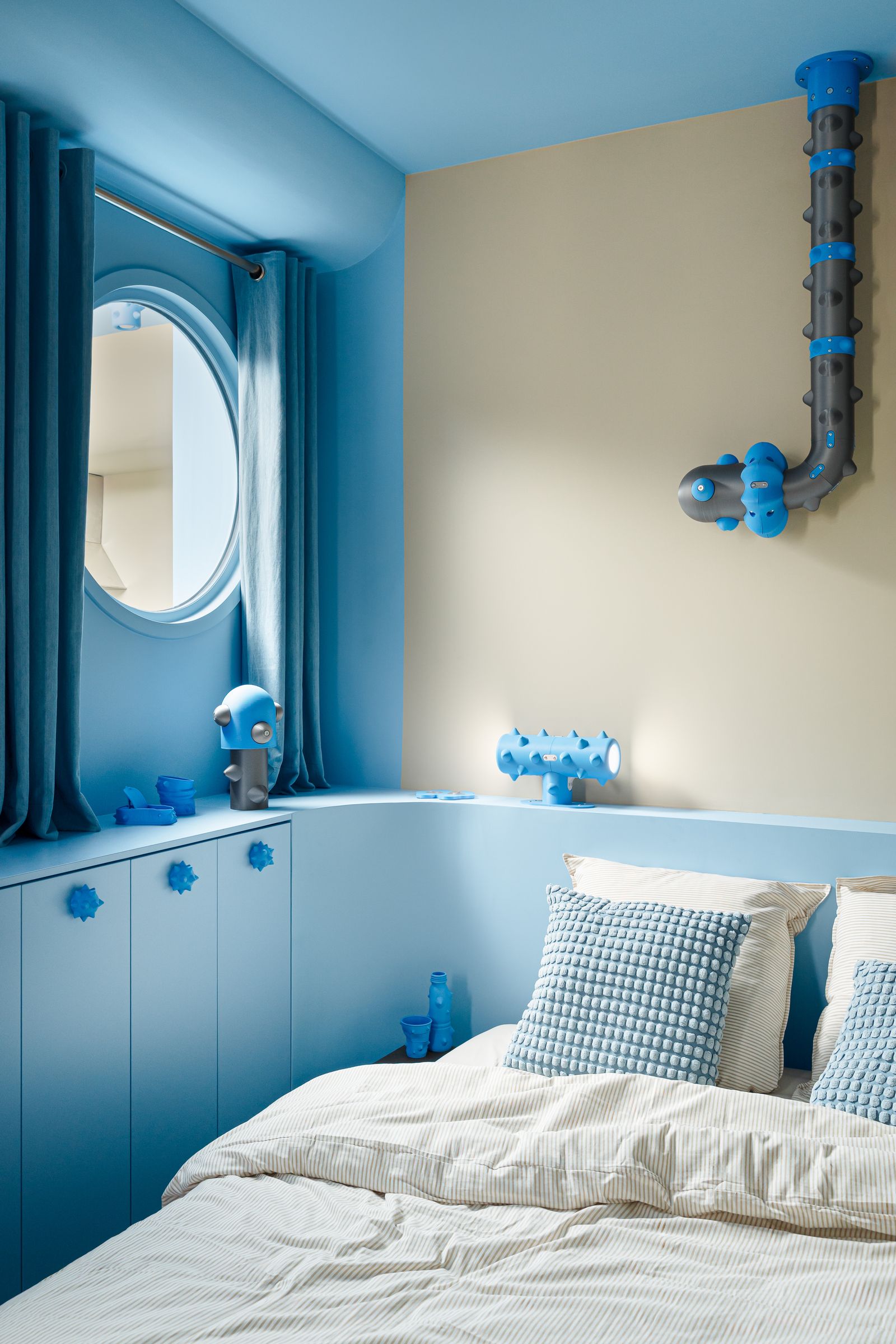 camera da letto mobile azzurro che prosegue nella testata oblò