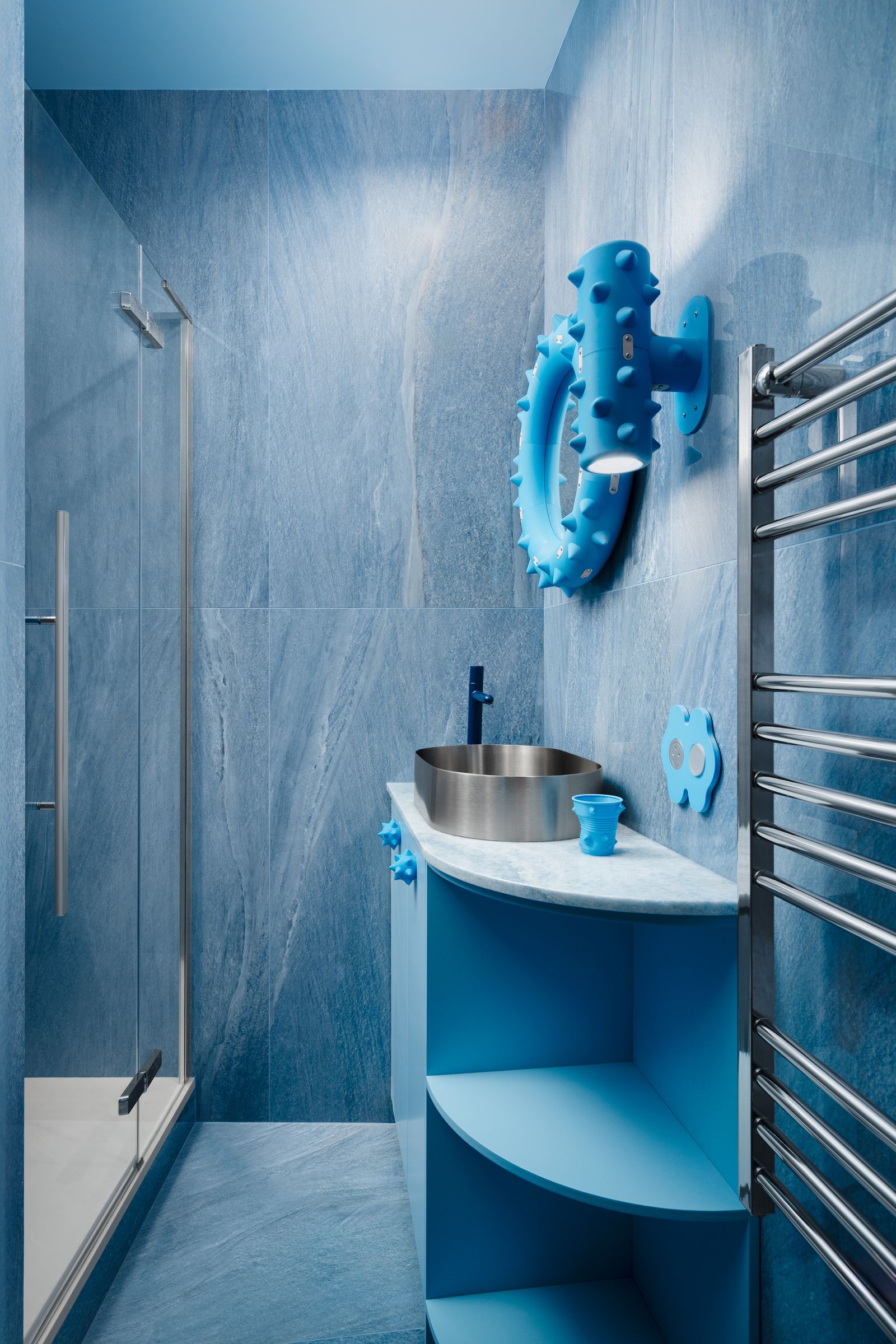 bagno in marmo azzurro mobiletto azzurro con lavabo in metallo e ripiani scaldasalviette doccia specchio e applique