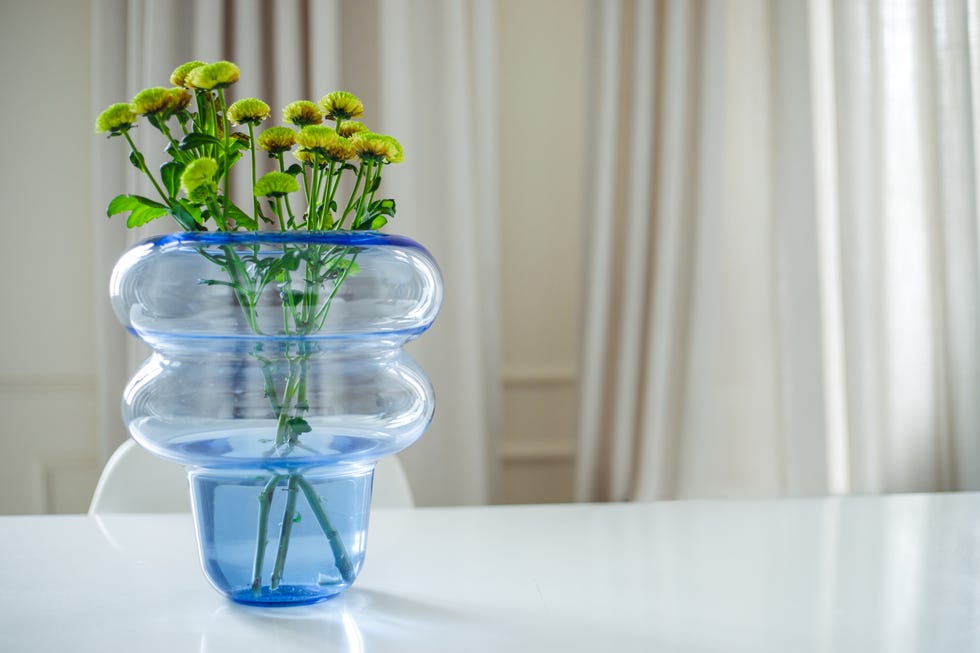 A vase of colored blue glass with flowers is on the table in the living room, copy space, front view a vase of colored blue glass with flowers is on the table in the living room, copy space, front view