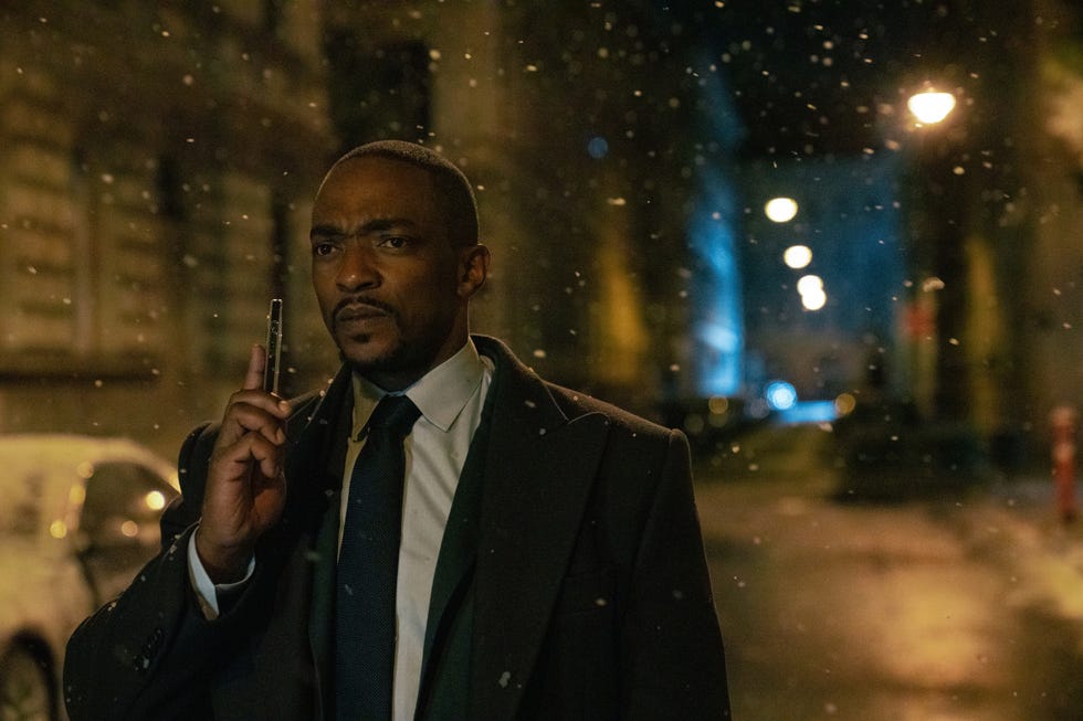 Man in a suit holds a phone to his ear in a dimly lit snowy street. Man in a suit holds a phone to his ear in a dimly lit snowy street.