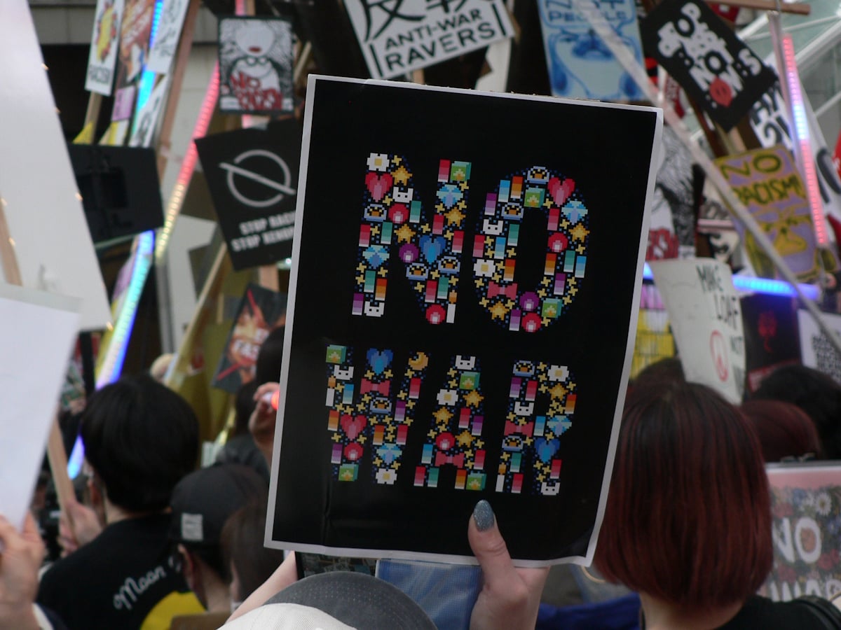 A protestor at the March 10th Tokyo protest against the Iran War holds up a "NO WAR" sign