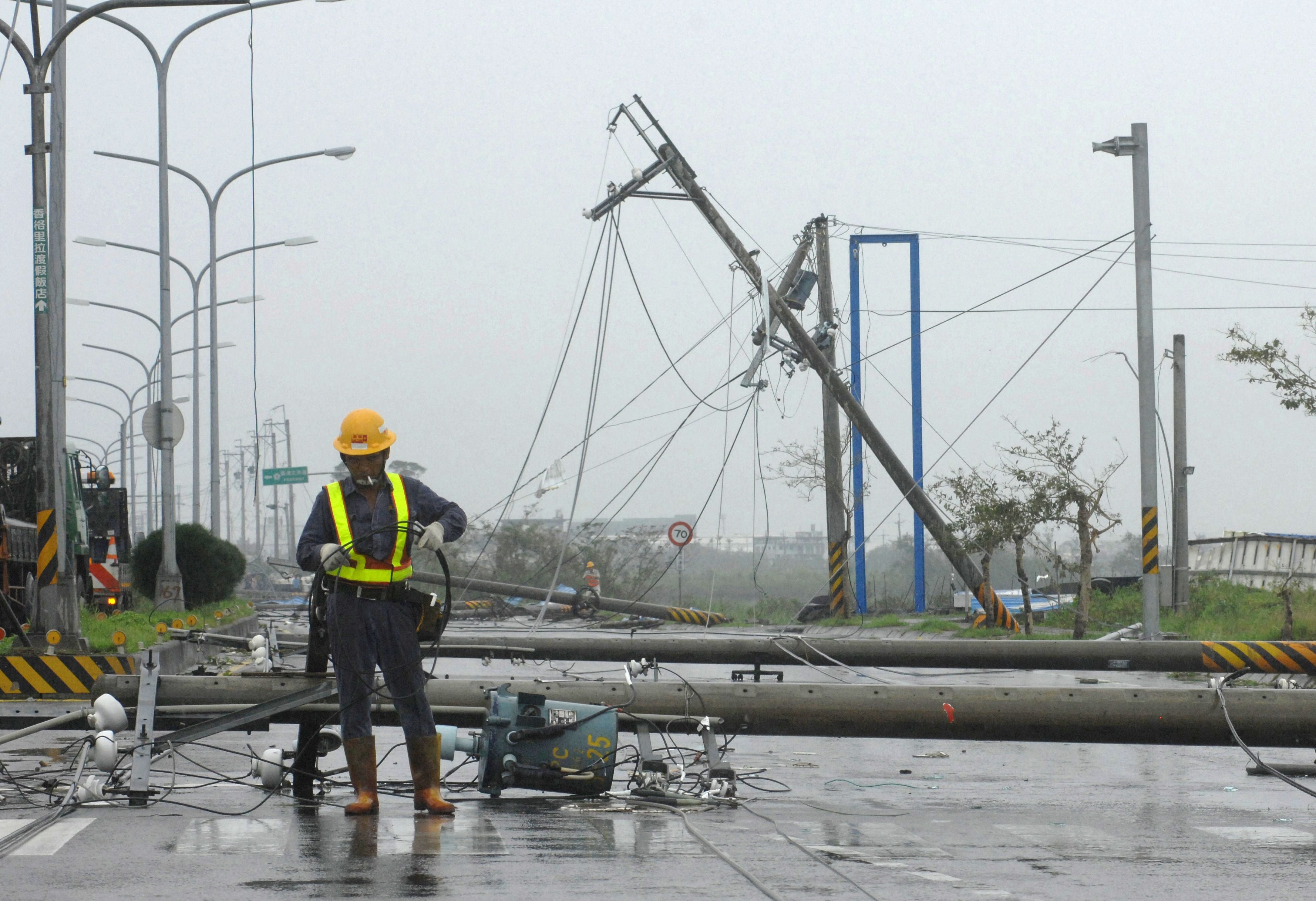 Workers attempt to repair electricity lines and poles that were toppled by Typhoon Jaigmi in Suao, a coastal town in Taiwan's northeastern Ilan county