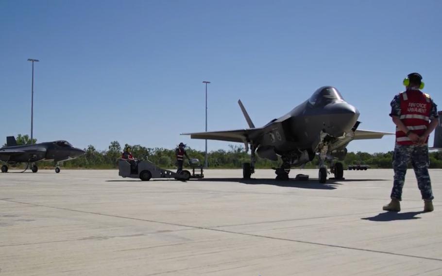 Fighter jets on an airfield with ground crew and support equipment nearby.