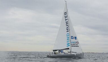 A sailboat named "Wind Hunter" navigates choppy waters under a cloudy sky.