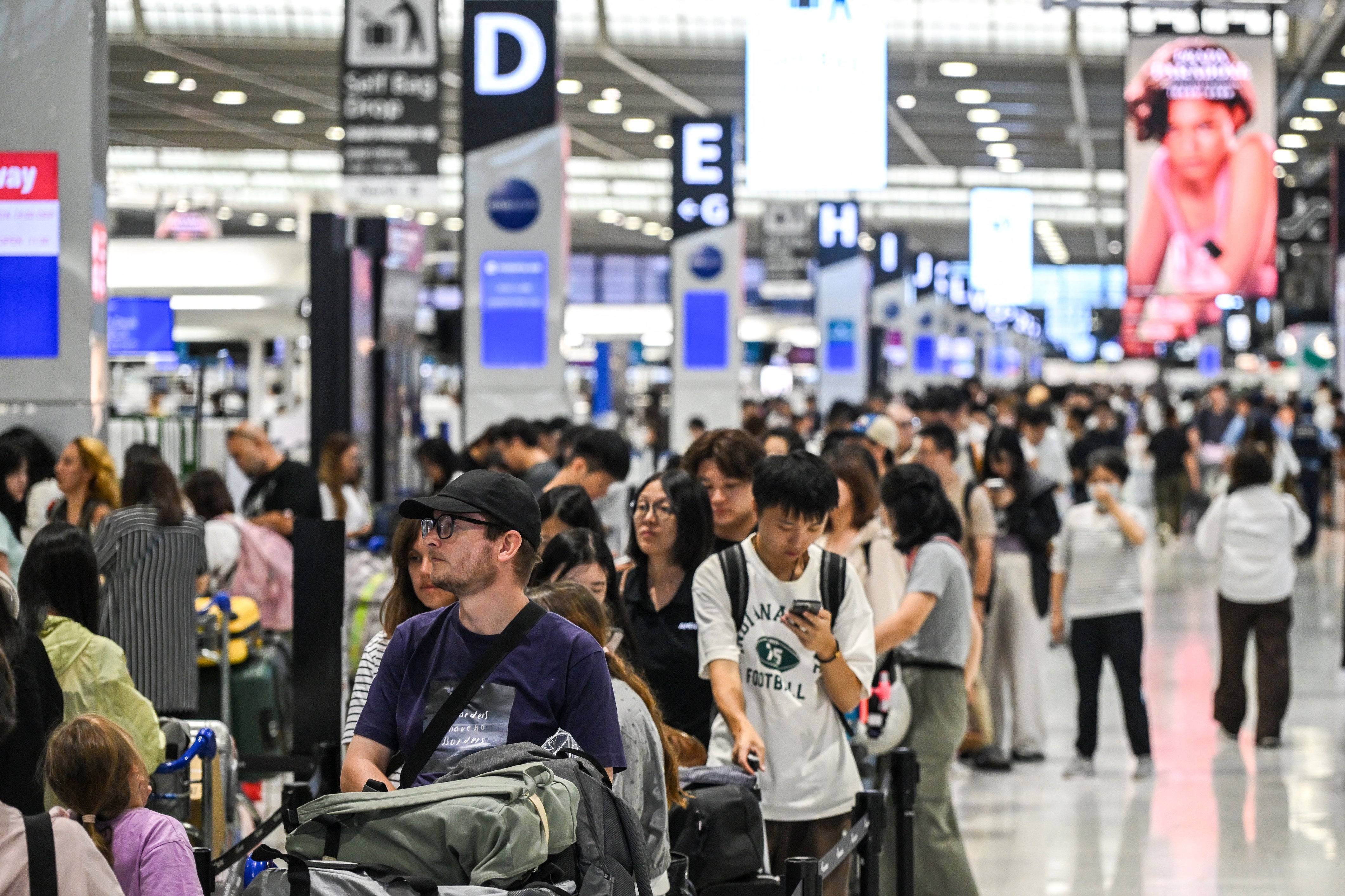 People line up in front of the check-in counter at the Narita airport in Narita, Chiba, Japan