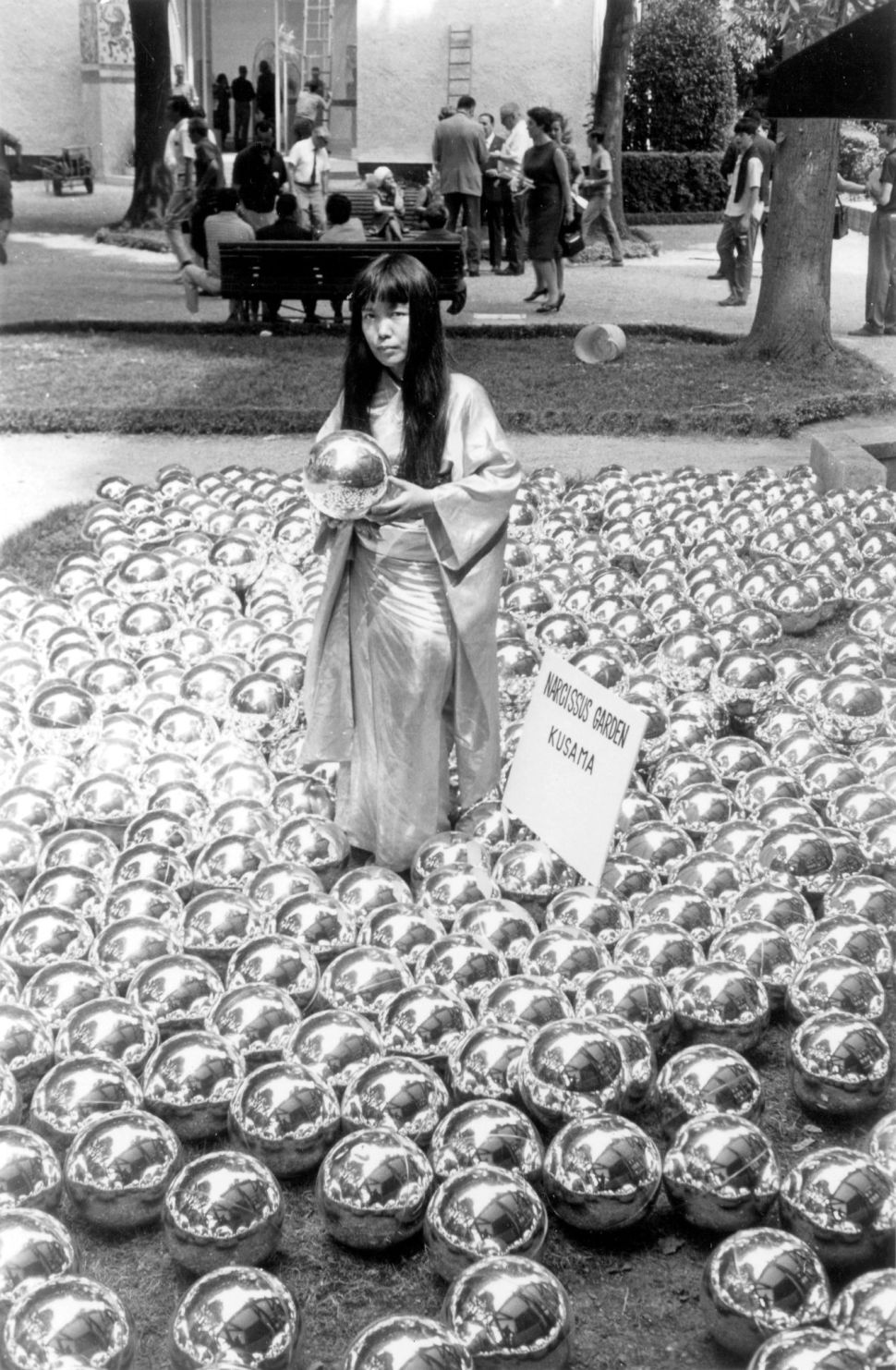 A young Yayoi Kusama stands amid hundreds of mirrored spheres in her 1966 Narcissus Garden installation at the Venice Biennale.