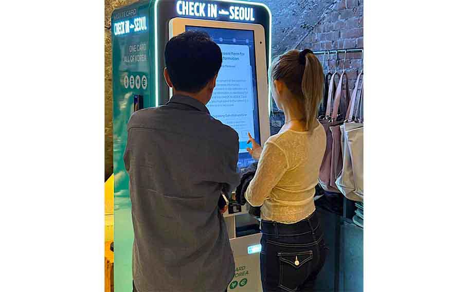 A couple using a “Lotte Card, Check in Seoul” kiosk.