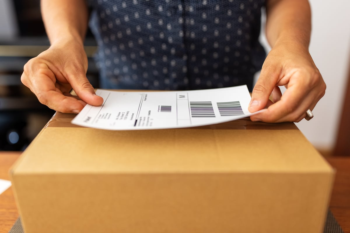 A person putting a shipping label on a package.