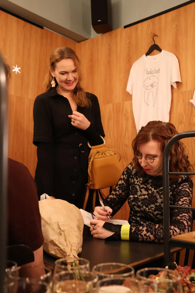 Autogrāfu sniegšanas brīdis kopkrājuma "Gājēji" atklāšanas vakarā "Zvaigzne Cafe".