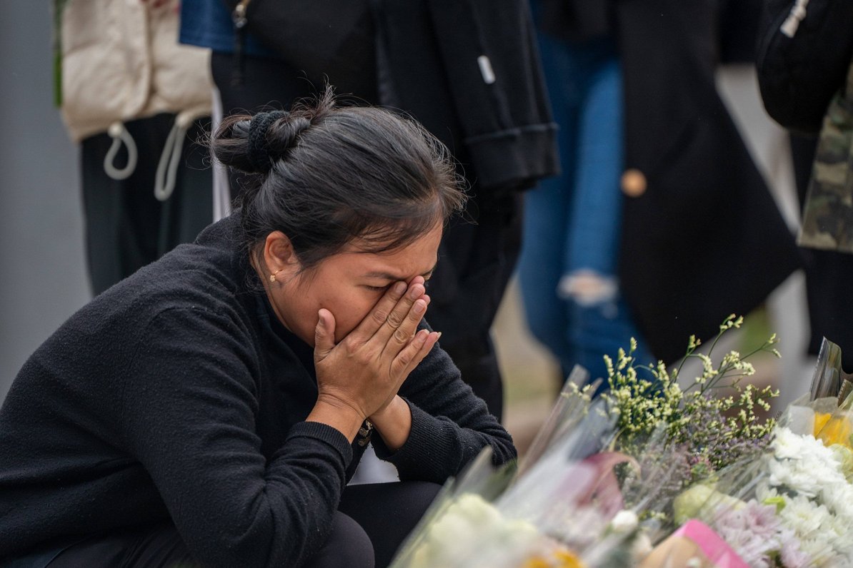 Sieviete 30. novembrī sēro pie ugunsgrēka izpostītā māju kompleksa Honkongā