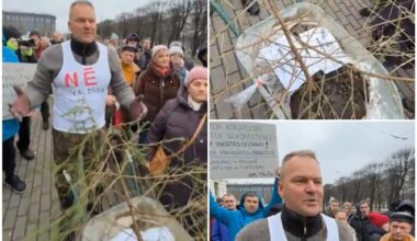Protestētāju Pēteri Dimantu ar mēslu čupu ķerrā, eglīti un kreklu “NĒ valdībai” nelaiž garām Ministru kabineta ēkai
