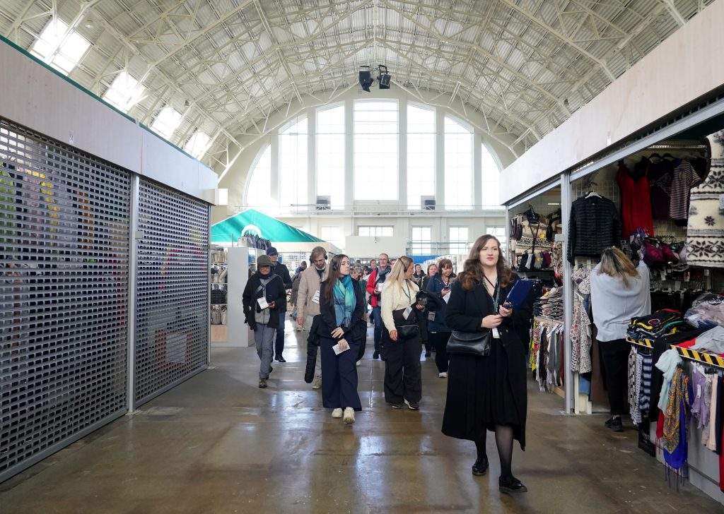 SIA “Rīgas nami” pārstāve Dita Vīndedze (priekšplānā) Rīgas Centrāltirgū (RC), kura laikā ārvalstu eksperti – pilsētplānotāji un arhitekti apmeklē tirgu, lai izstrādātu attīstības priekšlikumus Rīgas vēsturiskajam centram, īpašu uzmanību pievēršot RC un tā pieguļošajām teritorijām.