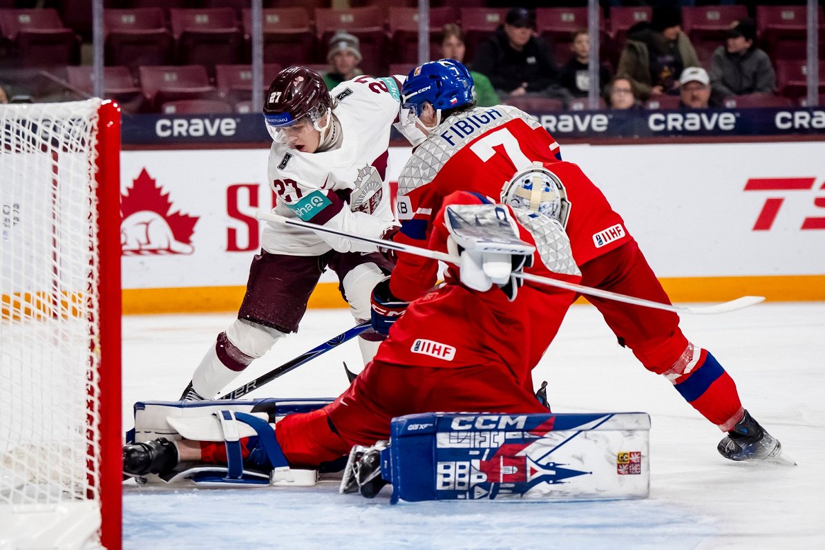 Latvijas hokejists Markuss Sieradzkis (pa kreisi) pie Čehijas vārtiem U-20 pasaules čempionāta spēlē