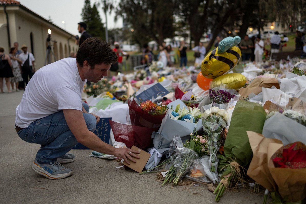 Cilvēki noliek ziedu pie Bondi pludmales slaktiņa vietas. Sidneja, Austrālija. 2025. gada decembris.