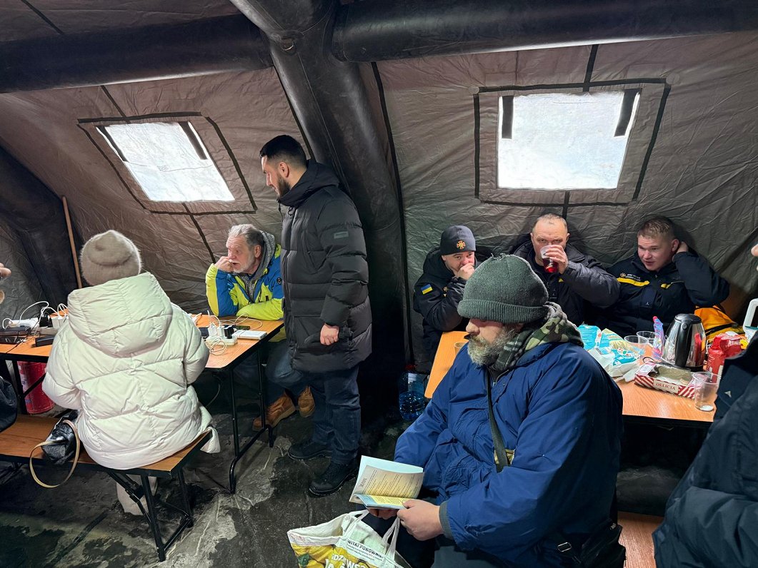 Cilvēki sildās Nesalaužamības punktā Kijivā, Dņipro rajonā