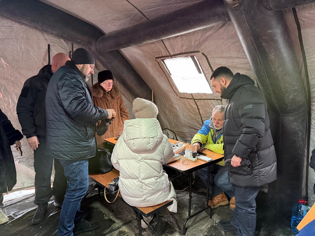 Cilvēki sildās Nesalaužamības punktā Kijivā, Dņipro rajonā