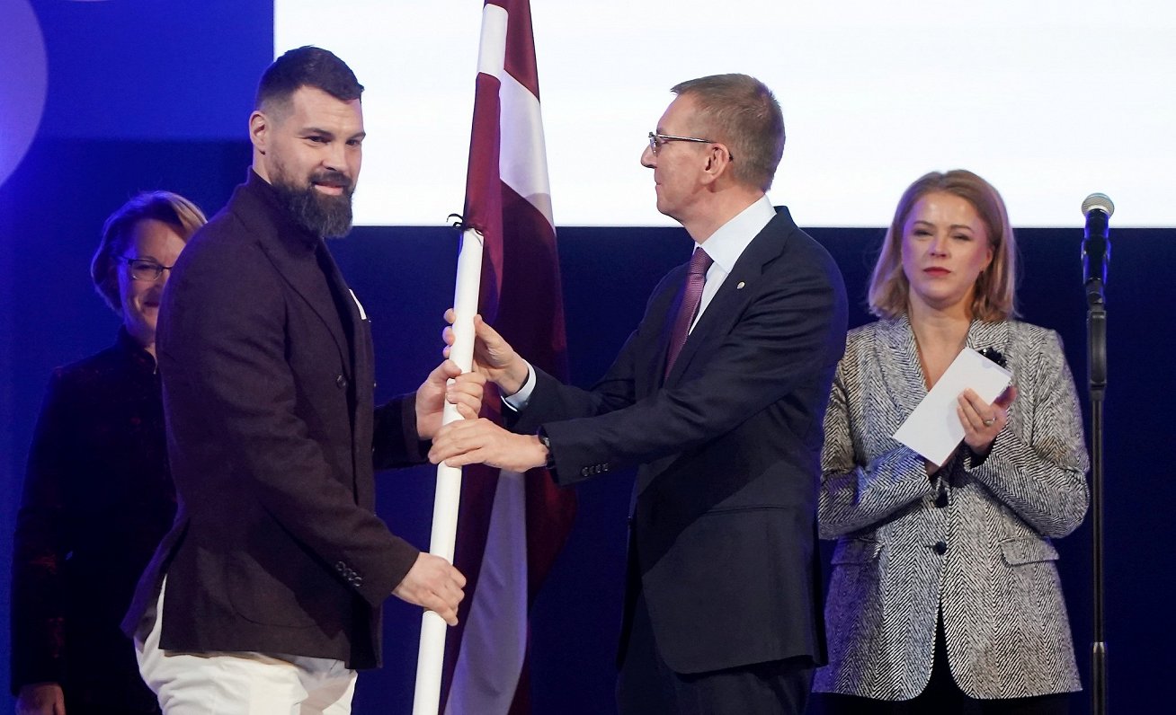 Hokejists Kaspars Daugaviņš (pa kreisi) saņem Latvijas karogu no Valsts prezidenta Edgara Rinkēviča