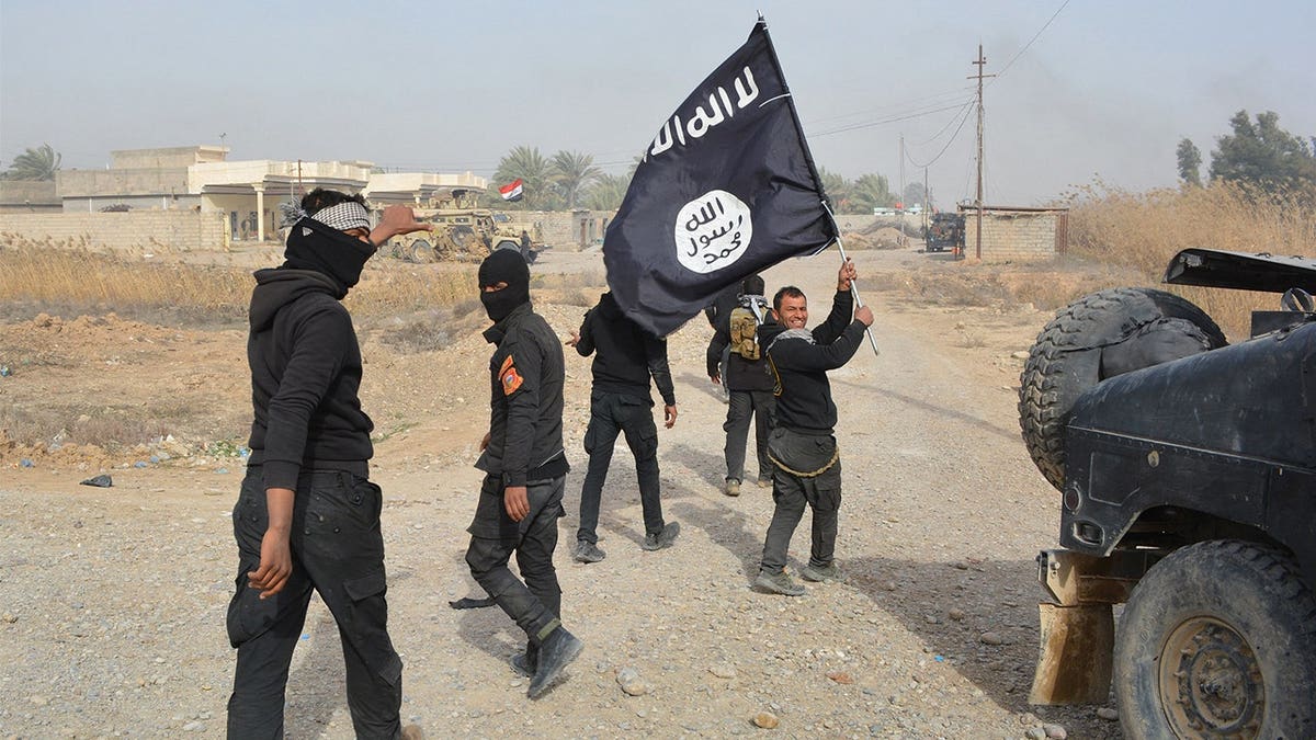 Iraqi government forces celebrate while holding an Islamis Sate (IS) group flag