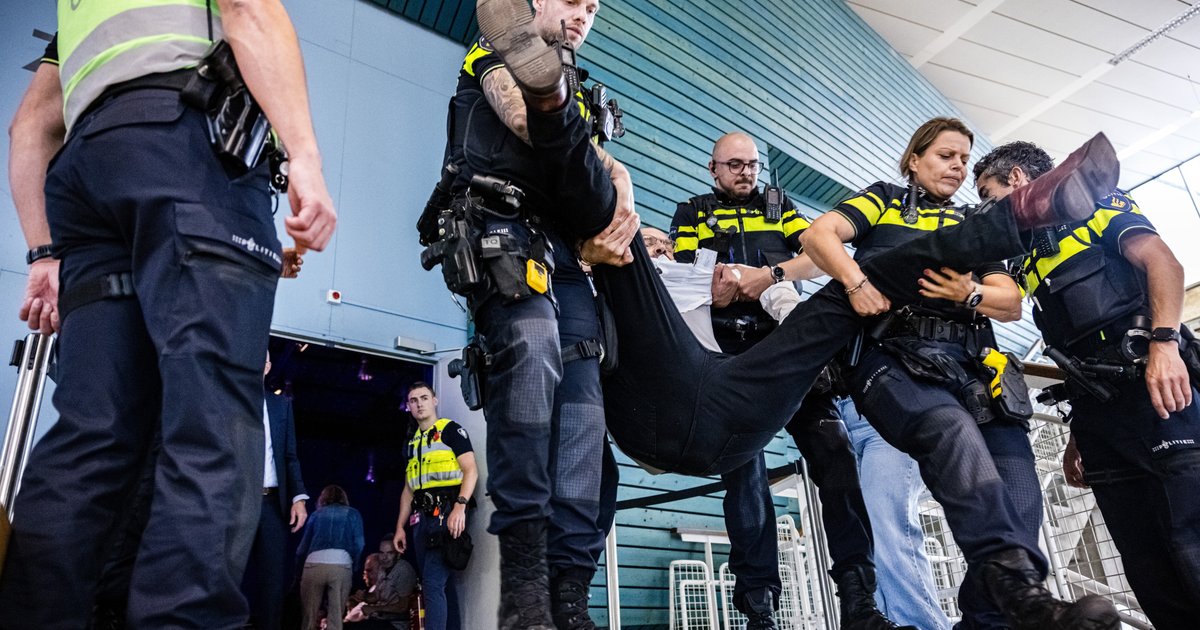 De politie verwijdert een demonstrant uit het auditorium van de Technische Universiteit Eindhoven