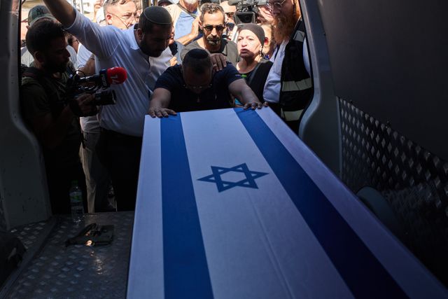 Een nabestaande rouwt bij de kist met de overleden Israëlische gijzelaar Yossi Sharabi, die begraven wordt in Israël. De uitruil van gijzelaars en gevangenen was onderdeel van het staakt-het-vuren.