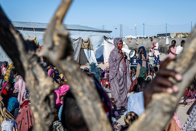 In het Tine-transitkamp in Tsjaad neemt het aantal vluchtelingen snel toe. De vrouw met de megafoon geeft instructies aan de nieuwkomers.