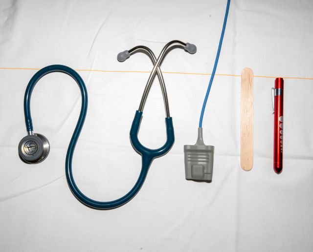 Medische instrumenten, waaronder een stethoscoop, een zuurstofsaturatie, een tongspatel en een ooglampje.