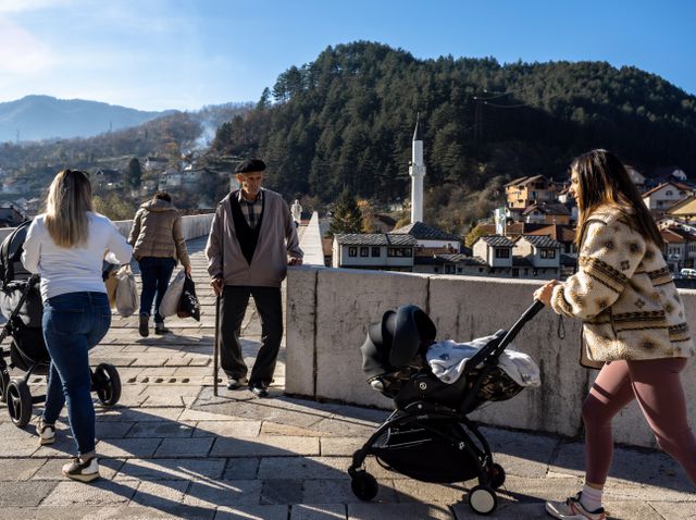 Jonge vrouwen duwen hun kinderwagens voort over de oude stenen brug in Konjic.