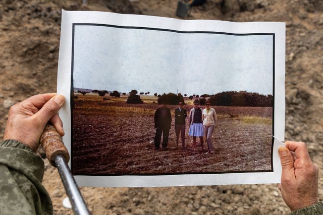 Een lid van de ARMH bekijkt een foto die rond 1980 op de opgravingslocatie is genomen. De vrouwen op deze foto zijn familieleden van Luis García Hernández, een van de vermiste mannen naar wie wordt gezocht. Tijdens hun bezoek troffen ze de man aan die met hen op de foto staat. Hij verzekerde hen dat hij had geholpen hun familielid te begraven in 1936.