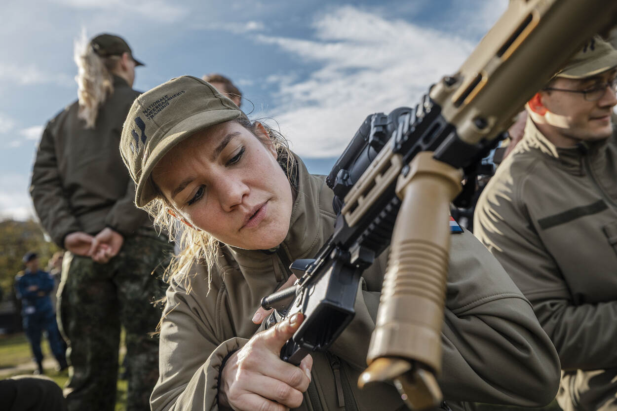 Een blonde, vrouwelijk militair controleert of haar geweer ontladen is.
