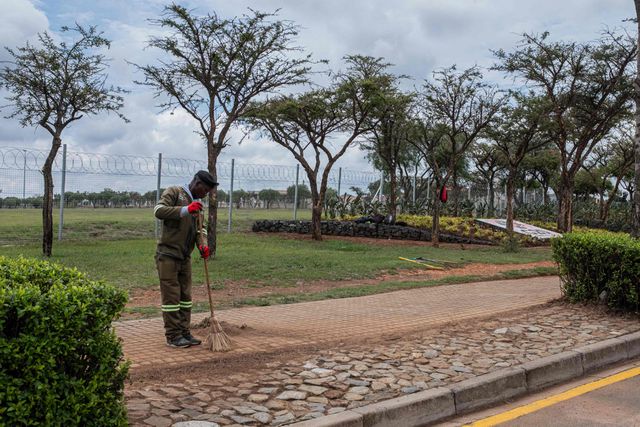 Een stratenveger aan het werk naast een vernield G20-bord buiten het Nasrec Expo Center in Johannesburg.