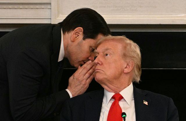Buitenlandminister Marco Rubio (l) fluiterst iets in het oor van president Trump.