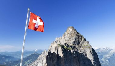 Swiss flag with Gstellihorn under a blue sky on a sunny summer day. Bernese Alps, Canton of Bern, Switzerland
