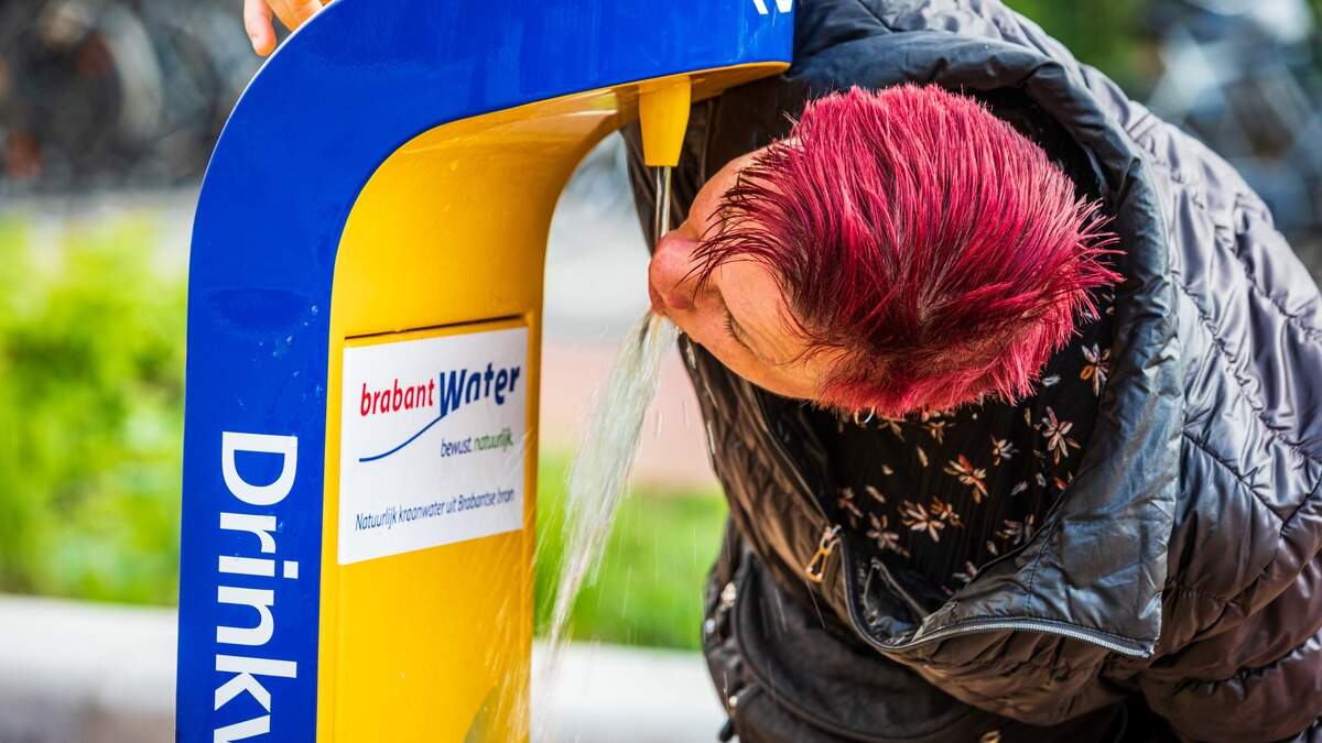 Een mevrouw die aan het drinken is bij een openbaar watertappunt.