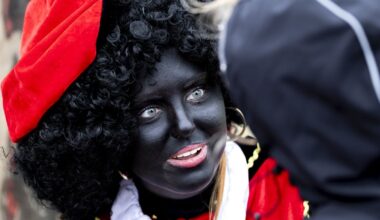 Een Zwarte Piet begroet kinderen tijdens een lokale intocht van Sinterklaas.