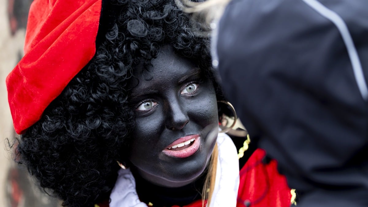 Een Zwarte Piet begroet kinderen tijdens een lokale intocht van Sinterklaas.