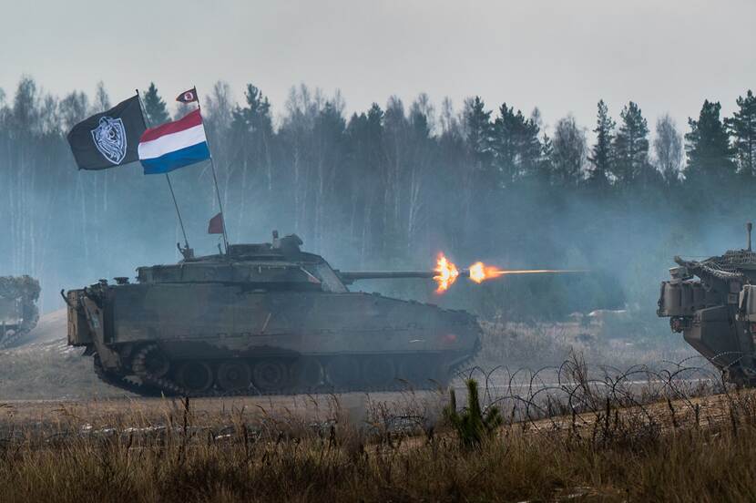 CV90 infanteriegevechtsvoertuig geeft vuur. NL-vlag wappert op het voertuig.