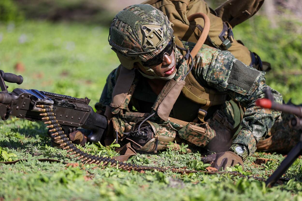 Een militair ligt op de grond met zijn wapen.