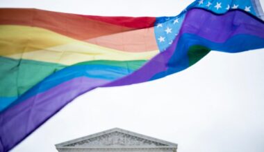 Een regenboogvlag wappert voor een gebouw 