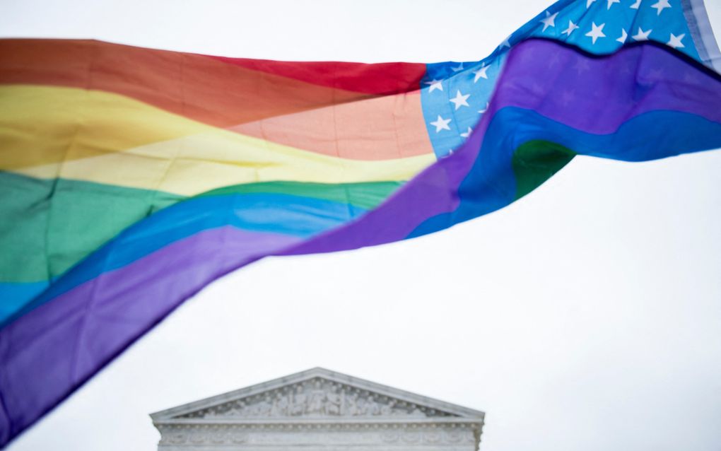 Een regenboogvlag wappert voor een gebouw 