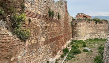 Dikke, deels afgebrokkelde stadsmuren, deels begroeid met onkruid.