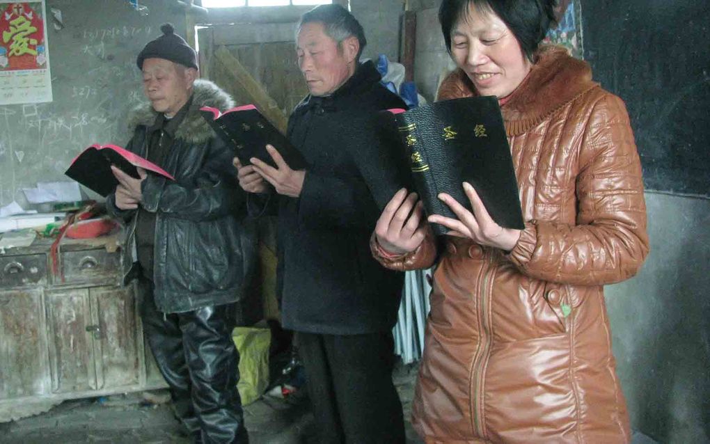 Twee mannen en een vrouw staan naast elkaar en lezen in de Bijbel.
