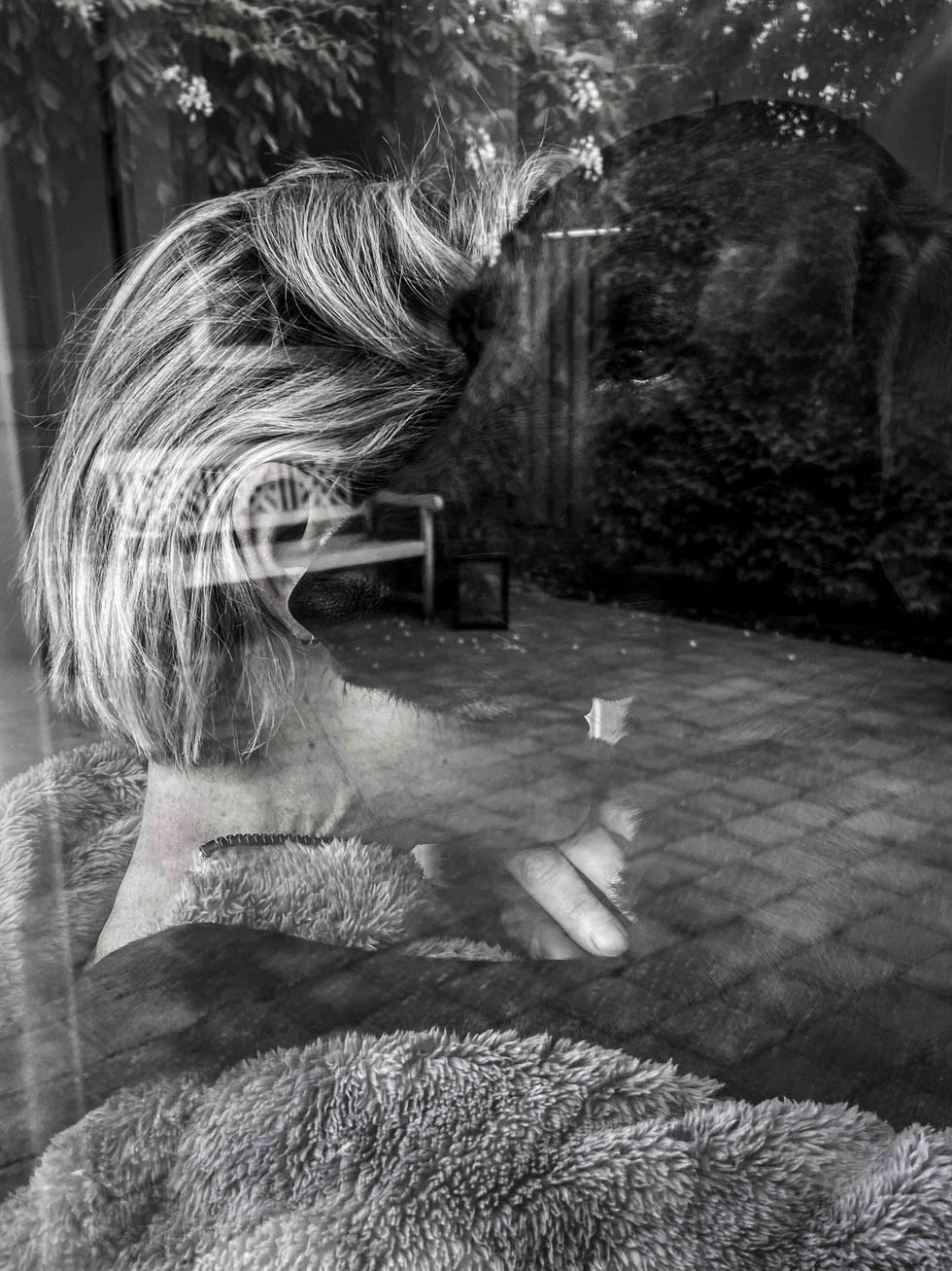 een vrouw en hond in zwart wit gefotografeerd door het keukenraam