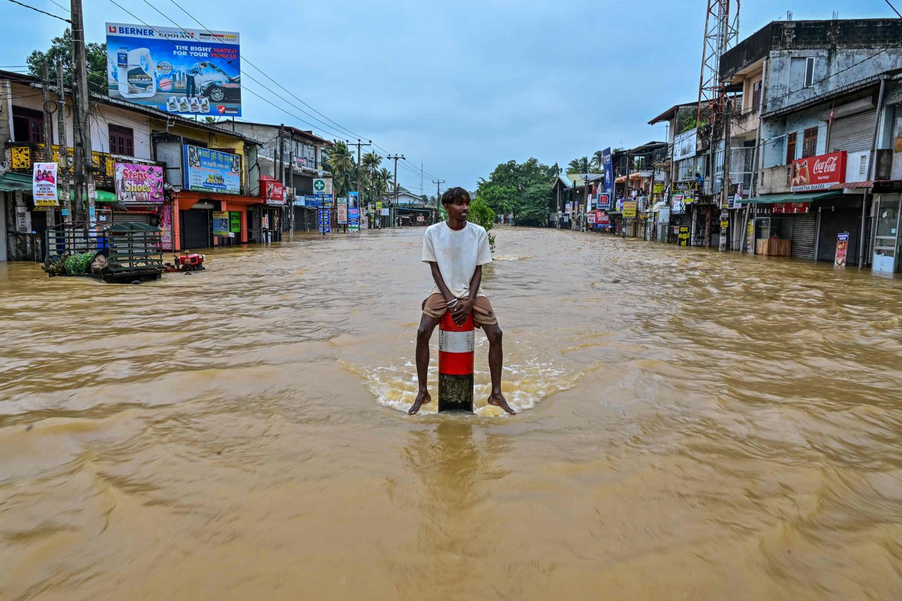 In het Sri Lankaanse Colombo probeert een man droog te blijven op een verkeerspaal. 