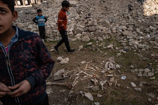 Kinderen naast  botten die ze uit verwoeste gebouwen in Tadamon hebben gehaald. 