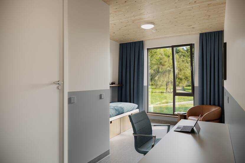 Een eenpersoons slaapkamer met stoel en bureau